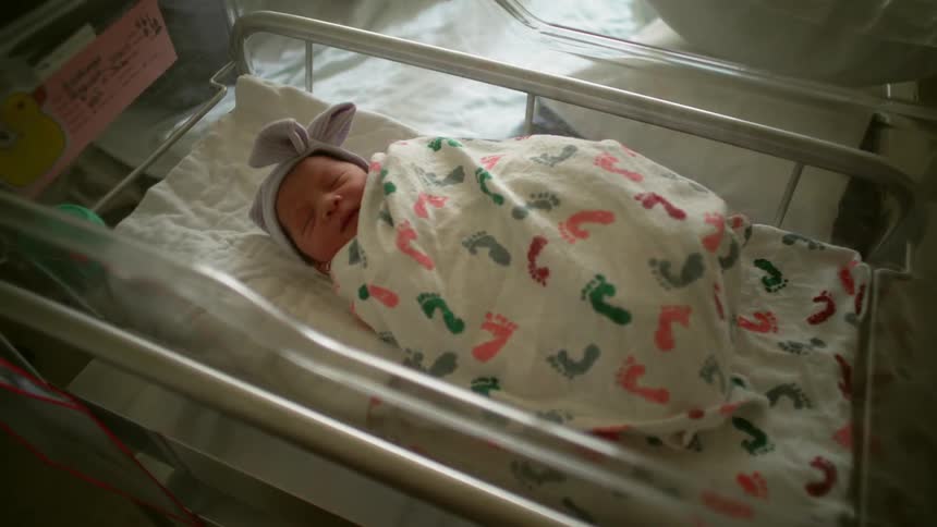 A baby swaddled in a bed inside a nursery