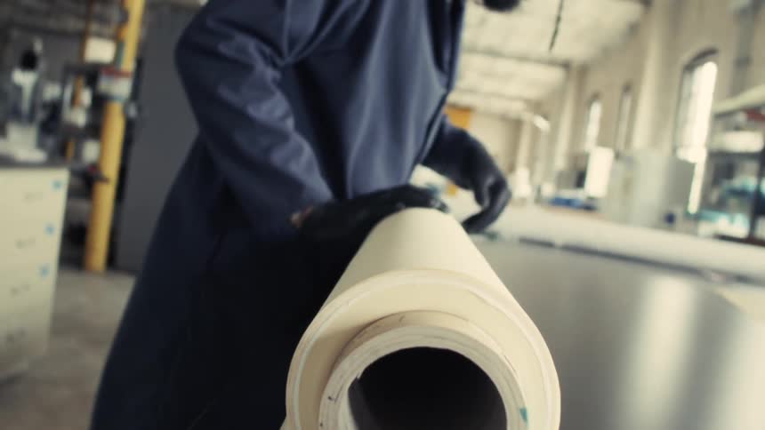 A man carries a long roll of paper and unrolls it on the counter