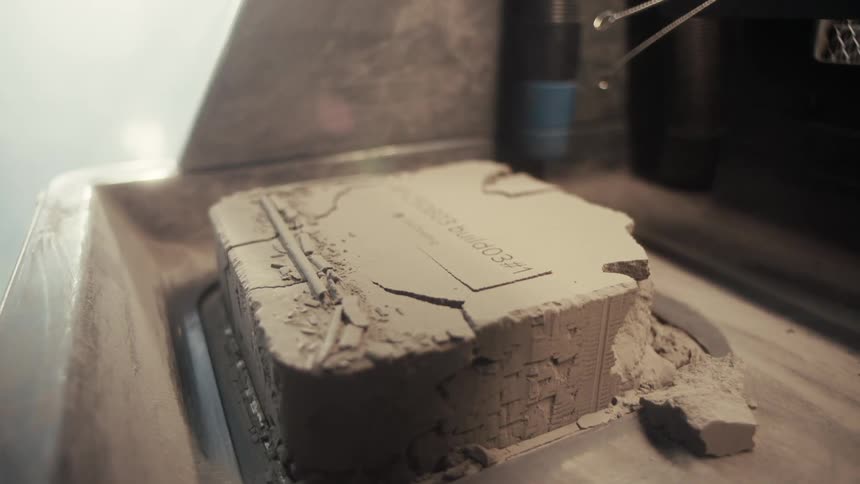 Partially revealed 3d print in powder block inside fabrication chamber
