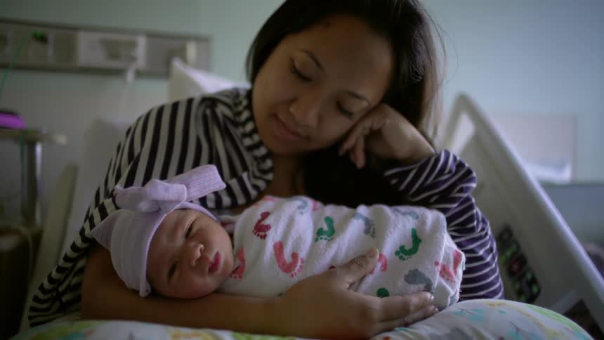 Woman holding and watching newborn baby sleep