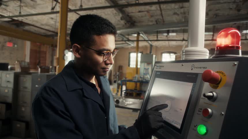 The worker is using the touchscreen on the machine