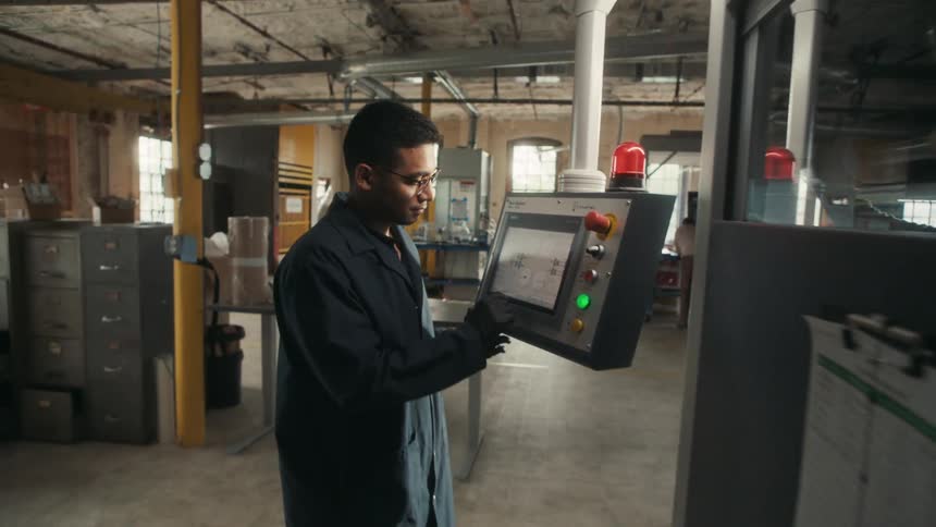 Worker operating control panel in a factory workspace