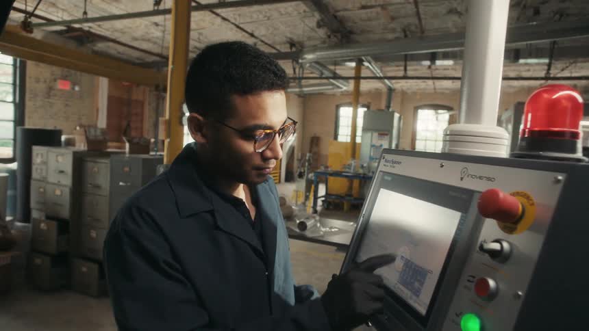 The worker is using the machine in the factory