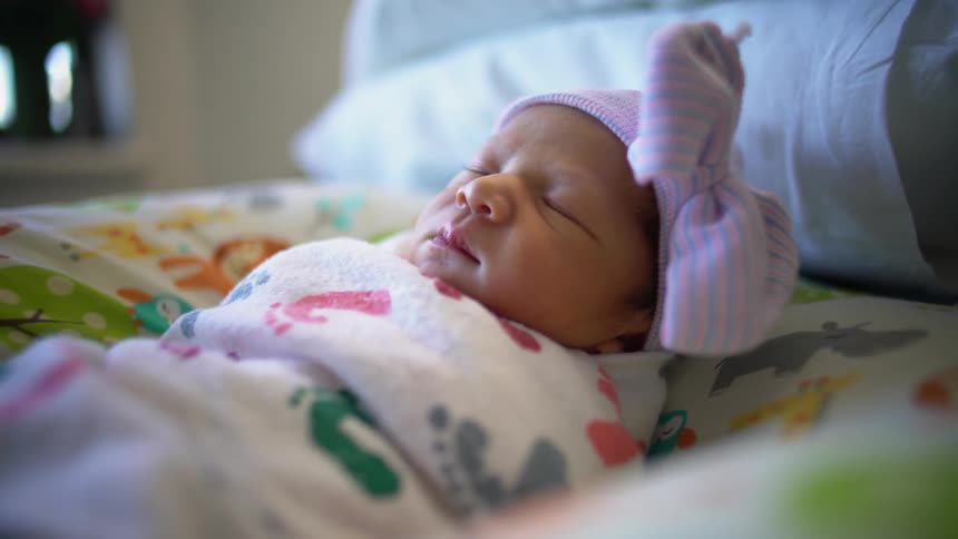 A swaddled baby girl on a bed