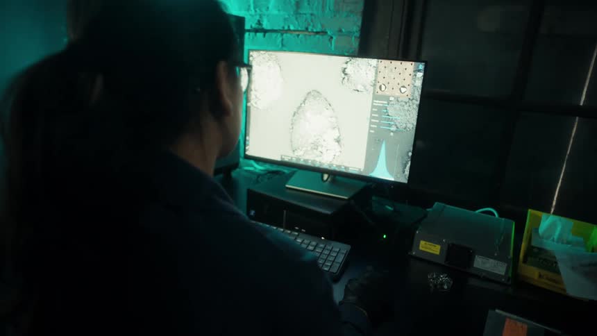 Woman analyzing 3d scan data on a monitor in a dimly lit lab