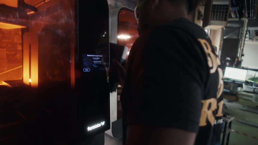The worker walks over to the machine and reaches inside