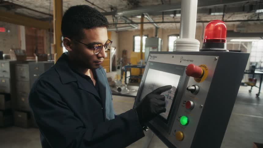 In the warehouse a man is using a touchscreen on a machine