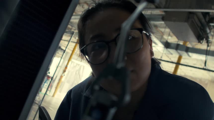 The worker is watching the robotic hands bend material