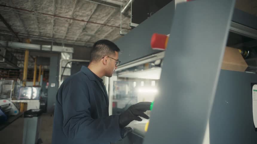 Young male worker uses the screen on an electrospinning machine in a lab factory