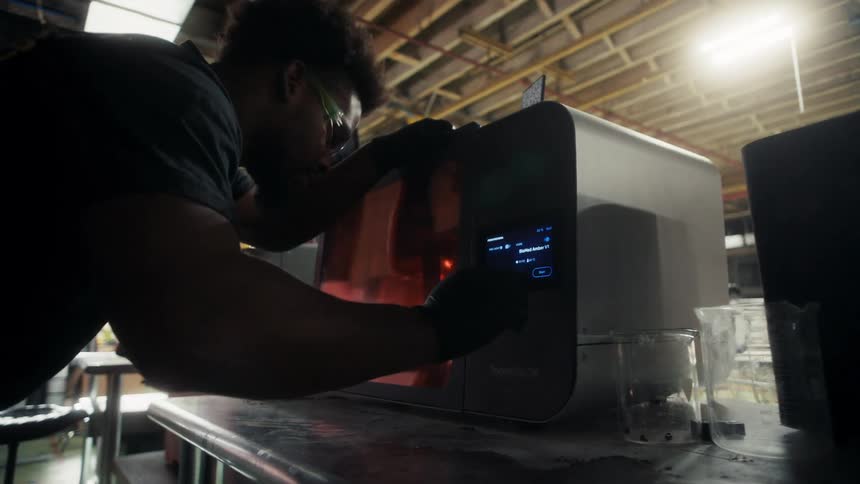 Person placing an object into an industrial 3d printer in a workshop setting