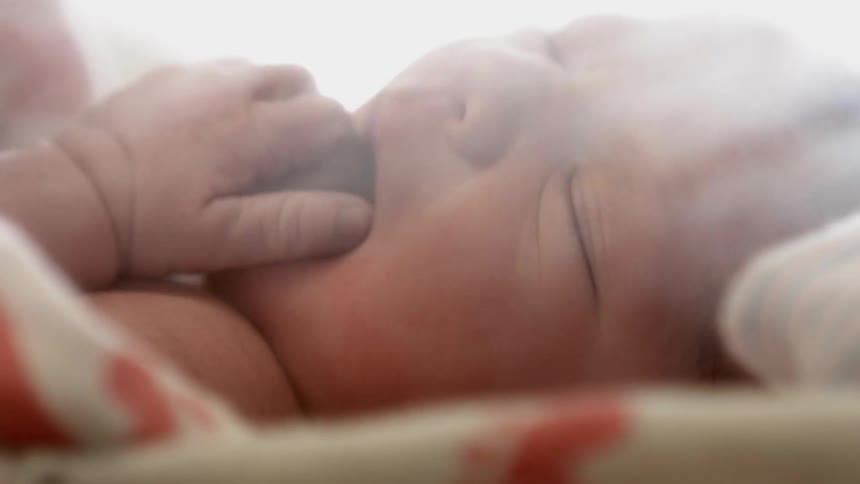 A baby has his hand in his mouth