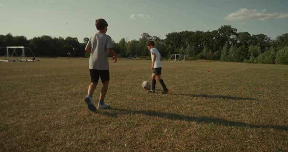 Outdoors in a field two children are playing soccer