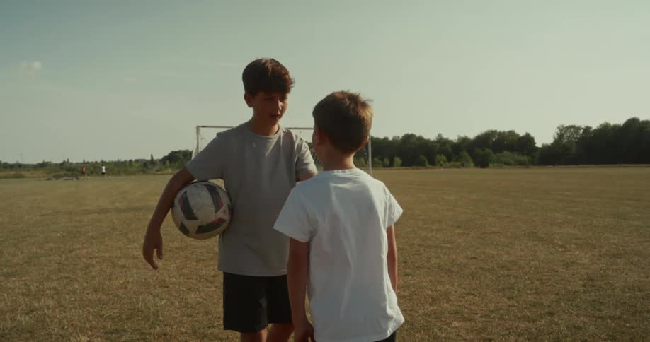 Two kids having a conversation on a soccer field