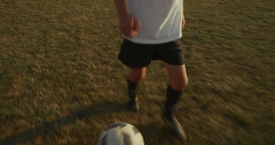A child dribbles a soccer ball down a field