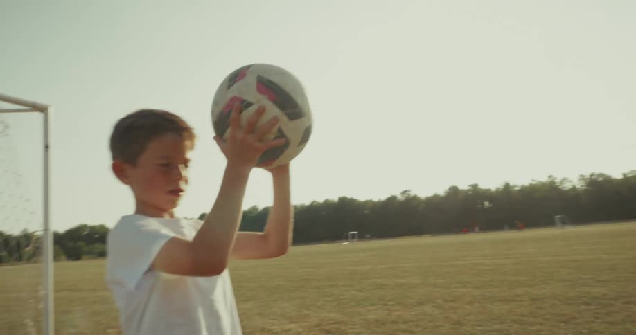 Two boys throwing a soccer ball to each other with one of them lying down on the field
