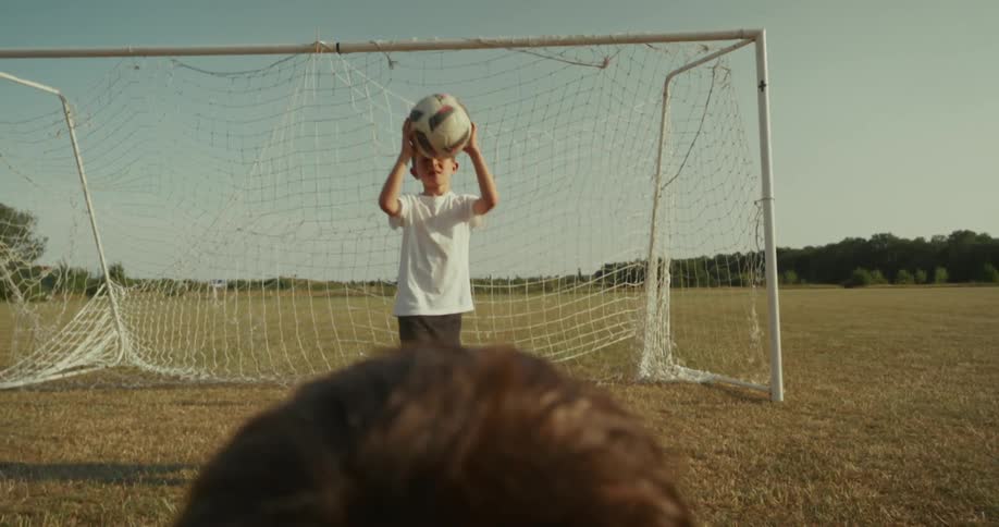 Two boys in a field throwing a ball with their hands to each other