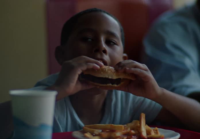 Father and son have burgers and fries in the restaurant