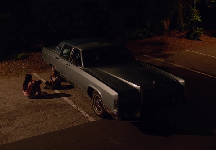 Two children sit together in the parking lot