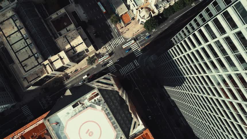 Buses and cars pass the tall buildings
