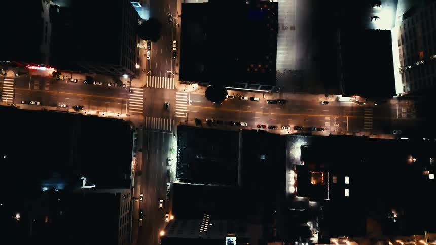 The cars drive through the dark streets at night
