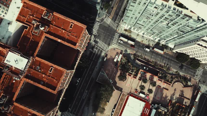 An aerial shot provides a birdseye view of a bustling city intersection with cars and buses navigating the streets the camera captures the intricate layout of buildings and roads showcasing the vibrant urban landscape from above
