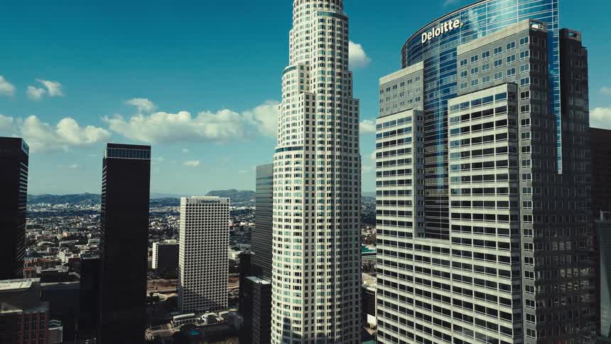 Downtown los angeles skyscrapers rise under a bright sky with the us bank tower and deloitte building prominently visible