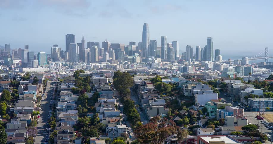 San franciscos downtown skyline rises in the distance behind rows of colorful residential buildings