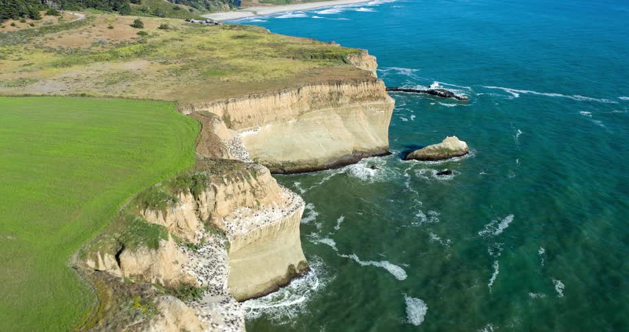 The ocean lines the cliffs before the beach