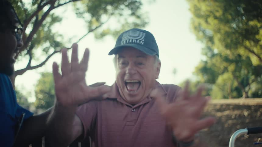 Two men are excitedly reacting to something on a smartphone while outdoors