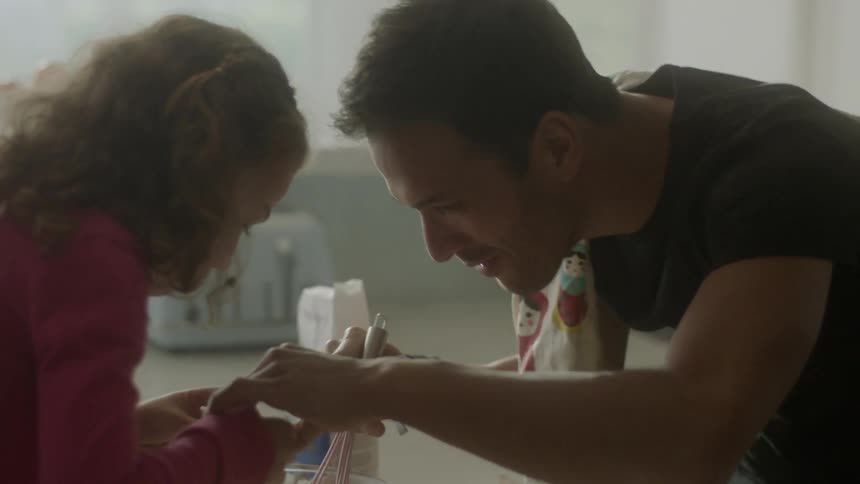 A man and young girl stir batter in the kitchen
