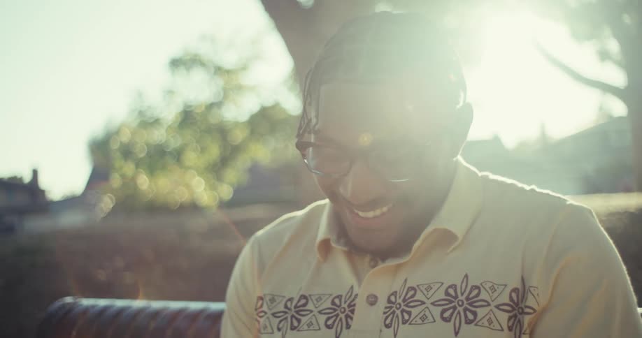 Man sitting on a bench outdoors with a happy expression