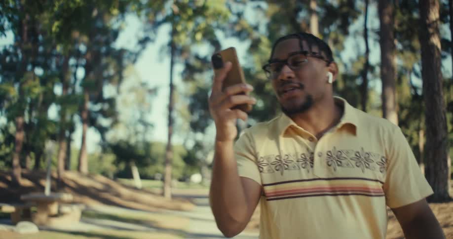 Man walking in a wooded area talking on his smartphone in a happy and vibrant manner