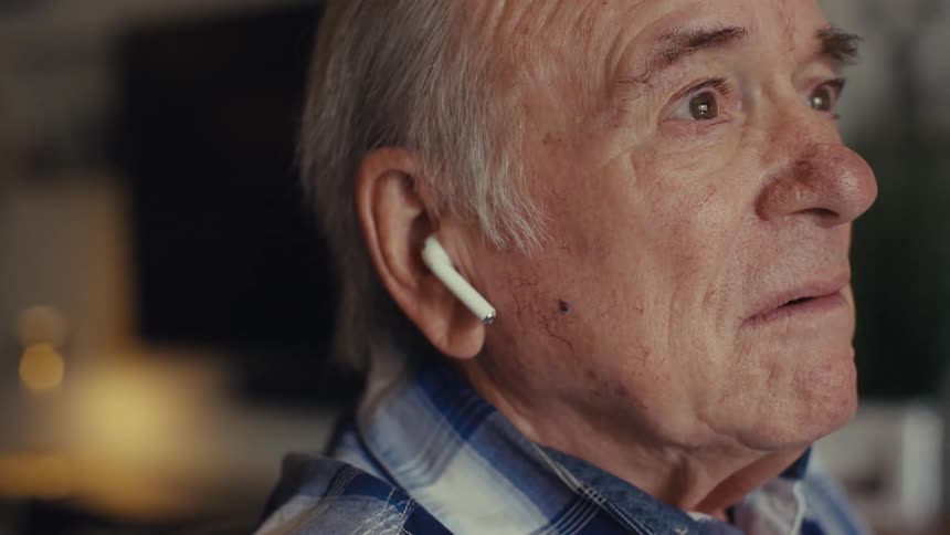 Elderly man talking using earbuds