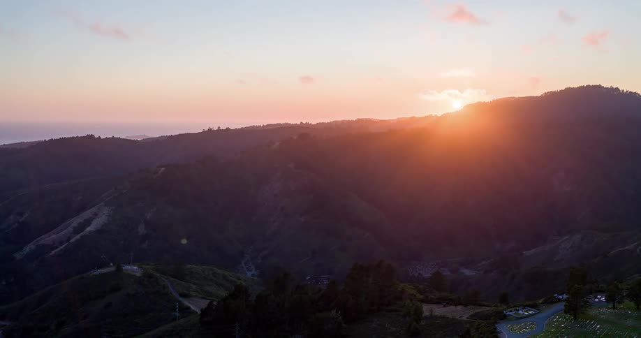 The sun sets behind the mountains bathing the landscape in orange hues