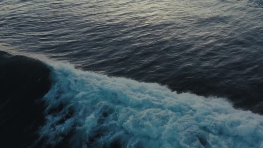 Aerial of a wave rapidly rolling across the ocean