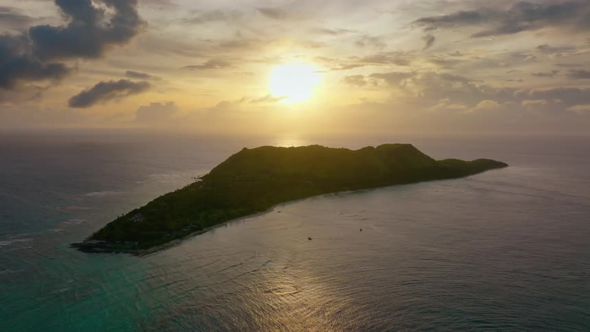 Aerial of a green island in a sea at sunset