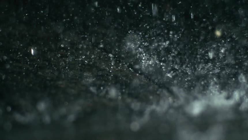Raindrops fall hard on the pavement outside during a storm