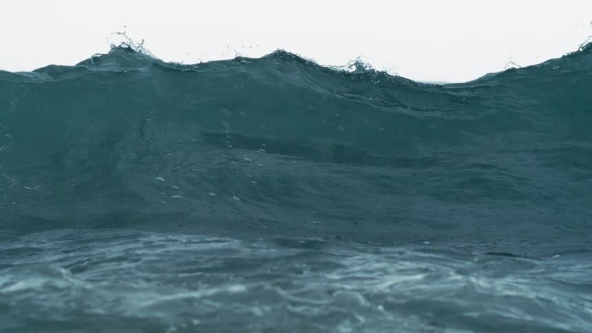 A wave curls and crashes in vivid blue water churning with white foam