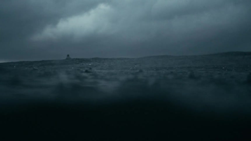 Dark stormy waters stretch into the distance under heavy clouds with a few distant objects barely visible on the horizon