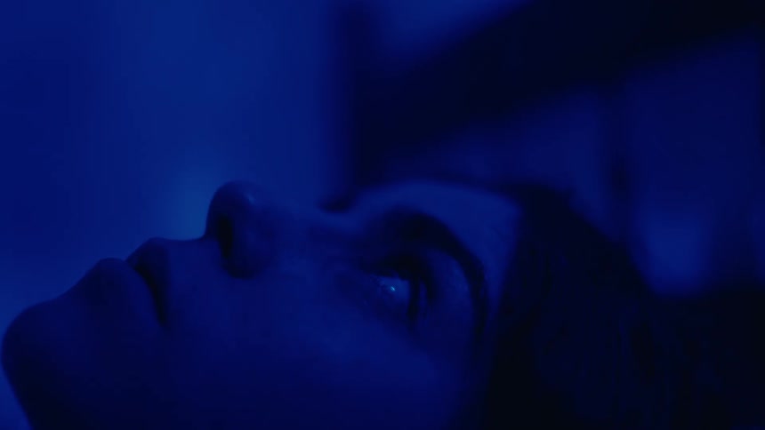 A girl is laying in bed looking at the ceiling