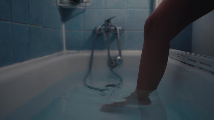 The video displays a static shot of a bathtub filled with bluetinted water featuring a silver faucet and shower hose the bathtub and surrounding tiles appear clean and wellmaintained