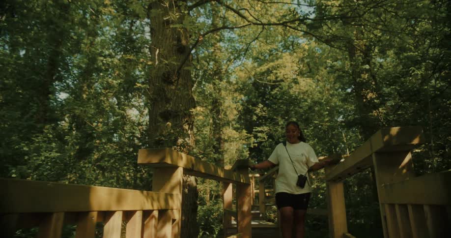 A woman hikes over the small bridge in the forest