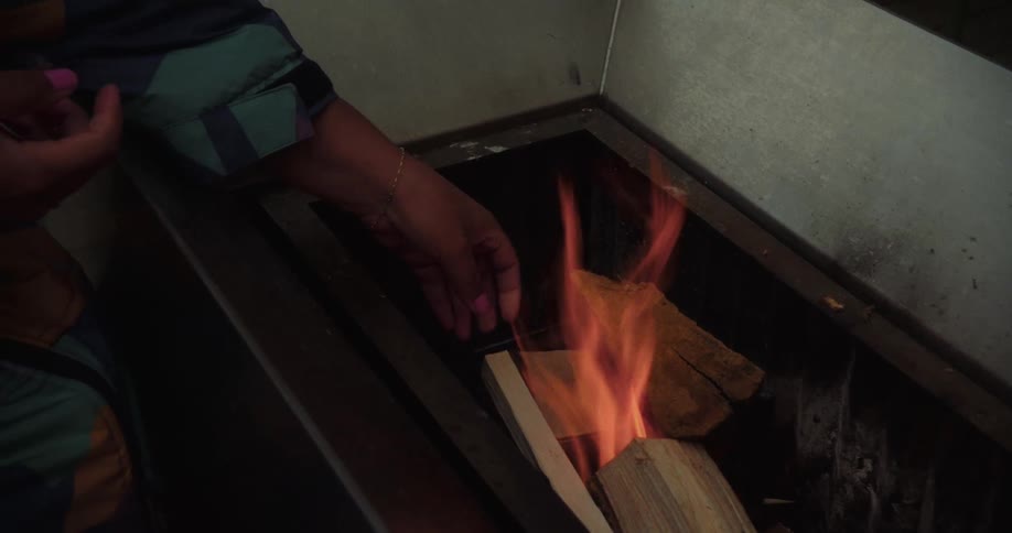 A person is adding wood to a burning fire