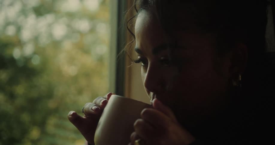 Woman in an indoor space or cabin drinking from a mug