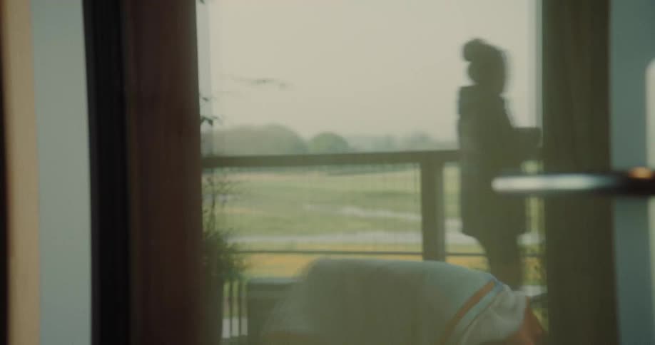 Reflection of a woman walking on a balcony seen through a door
