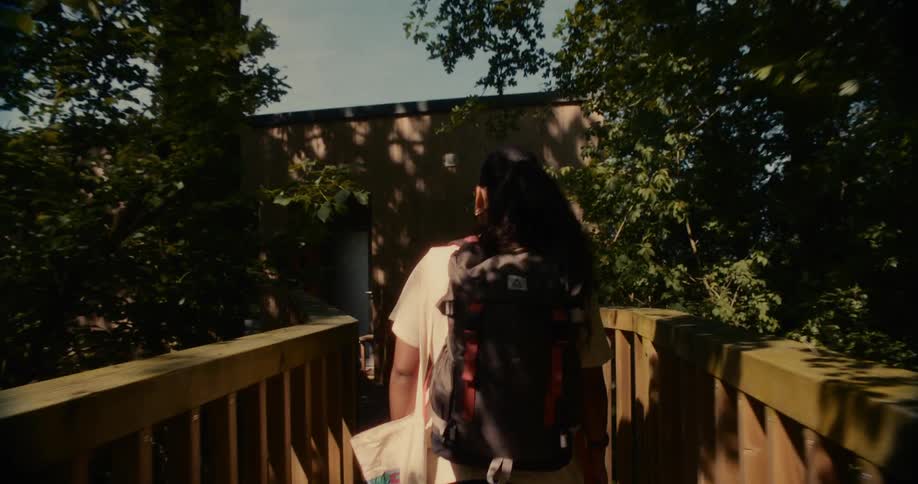 Woman with backpack walking in a natural area with a house in the background
