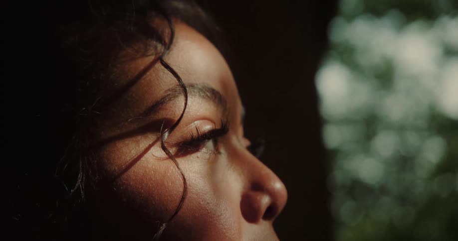 Woman observing in a natural environment with reflection of the sun and shadow on her face