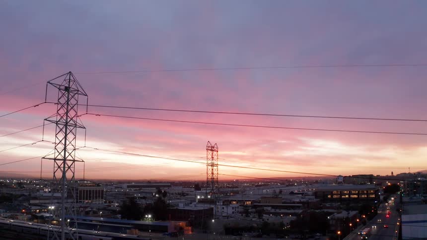Aerial shot of an overpass with traffic and a city in the background on a purple sky sunrise
