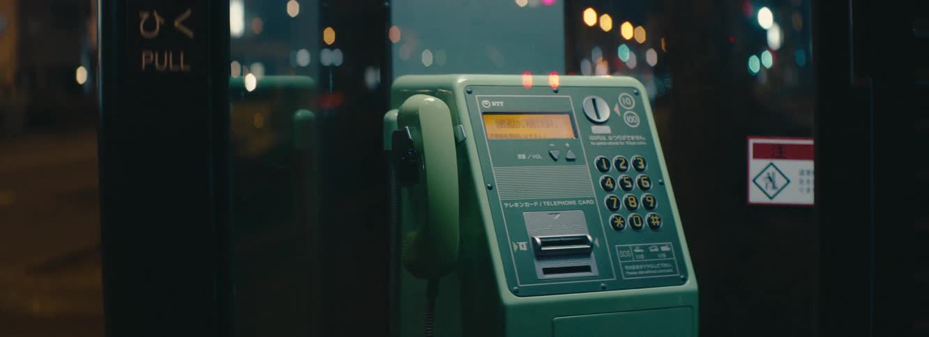 A public telephone booth in japan is cinematically lit at night with anamorphic bokeh