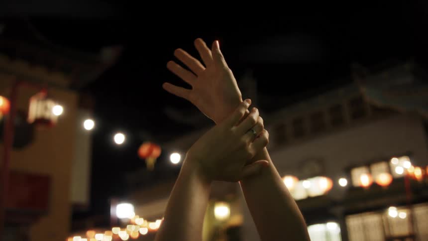 Closeup of a pair of hands pointing upwards in motion outdoors at night